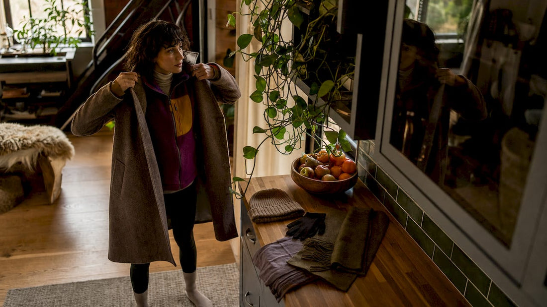 Woman layering winter clothing indoors