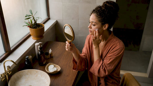 Woman applying moisturizer at vanity