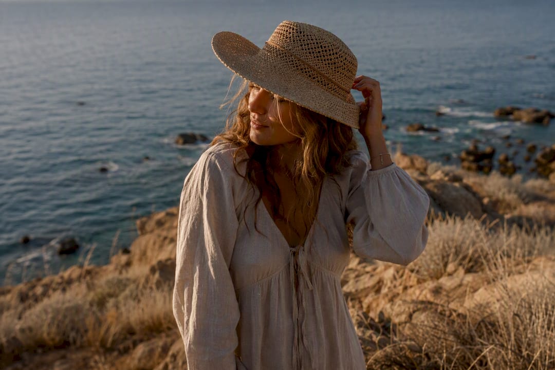 Woman in straw hat and boots on beach