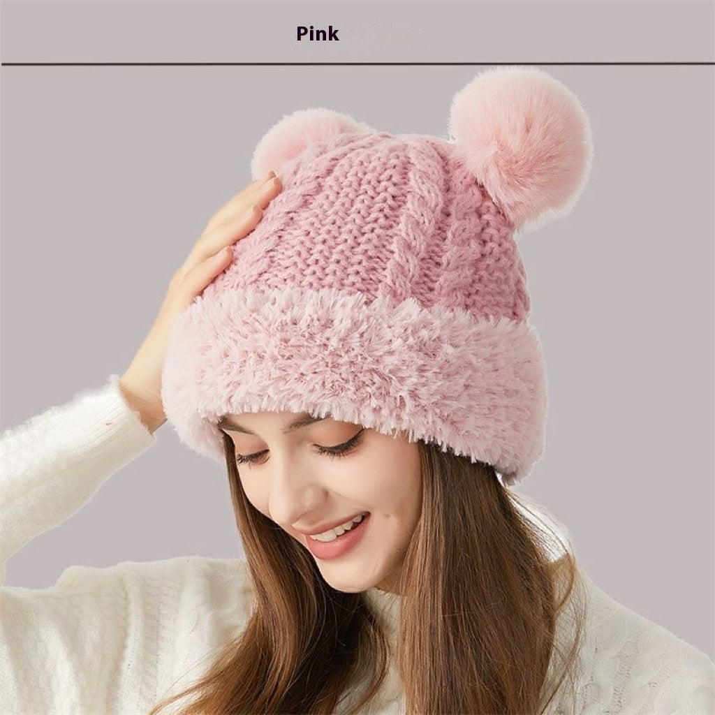 Woman wearing a pink knit winter hat with fuzzy pom poms, cozy beanie style