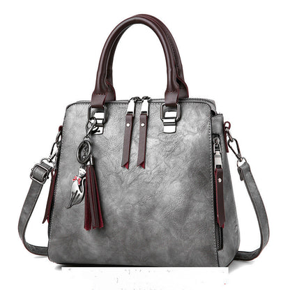 Gray leather handbag with brown handles, cat keychain, and detachable shoulder strap