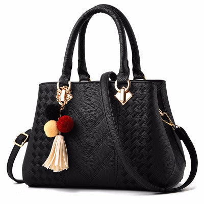 Elegant black leather handbag with textured pattern, gold accents, and tassel keychain