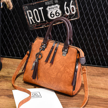 Brown leather handbag with dark handles on wooden table, Route 66 sign in background