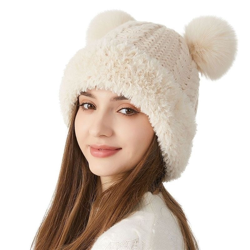 Woman wearing cream knit beanie hat with fluffy pom poms, winter fashion accessory
