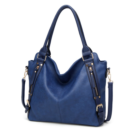 Large blue leather handbag with gold hardware and zipper accents on a white background