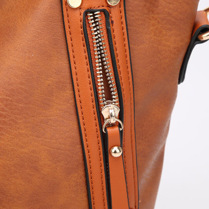 Close-up of brown leather bag with gold zipper and brown strap detail