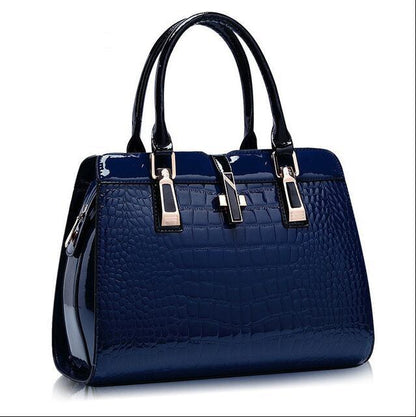 Glossy navy blue crocodile pattern handbag with black handles and gold accents