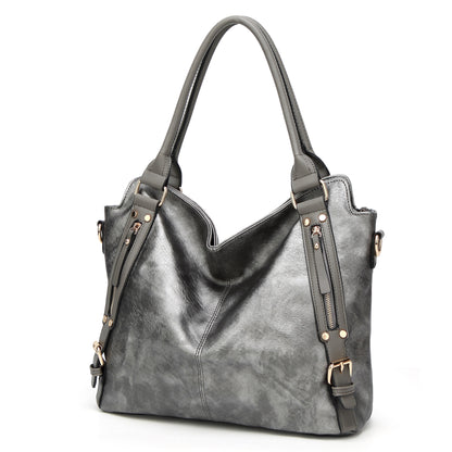 Gray leather tote bag with double handles, zipper detail, and gold-tone hardware on white background
