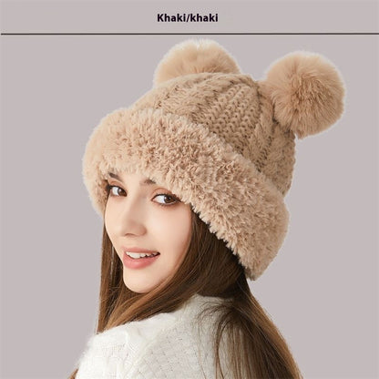 Woman wearing khaki knit beanie with faux fur trim and two pom poms, winter hat