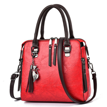 Red leather handbag with black handles, cat charm, and detachable shoulder strap