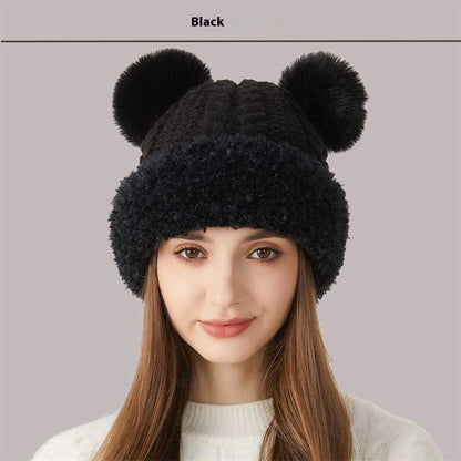 Woman wearing black knit winter hat with two pom-poms, cozy cold weather accessory