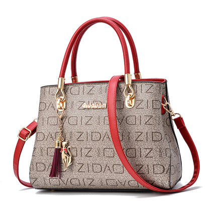 Stylish brown designer handbag with red handles, gold accents, and cat charm accessory