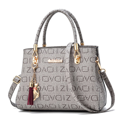 Gray leather handbag with gold hardware, ZIDQ pattern, and cat tassel keychain charm