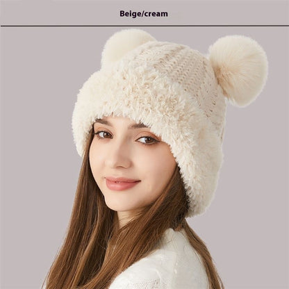 Woman wearing beige cream knit beanie hat with two pom-poms, winter fashion accessory