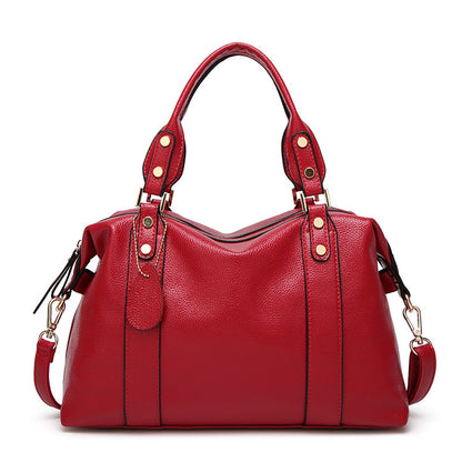 Red leather handbag with gold hardware and detachable strap on a white background